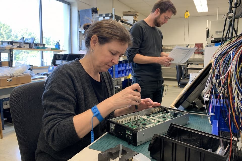 Illustrative scene of engineers assembling electronics and reviewing a production list